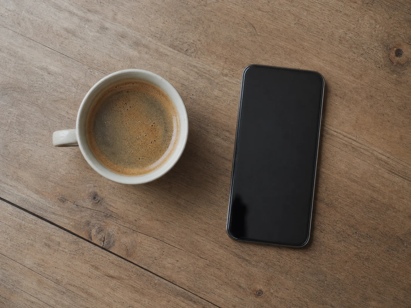 Overhead view of a phone and coffee illustrating how the Tinder Show Me feature filters your swipe pool